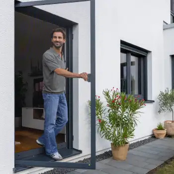 Mann öffnet eine maßgefertigte Fliegengitter Tür an einer modernen Terrasse